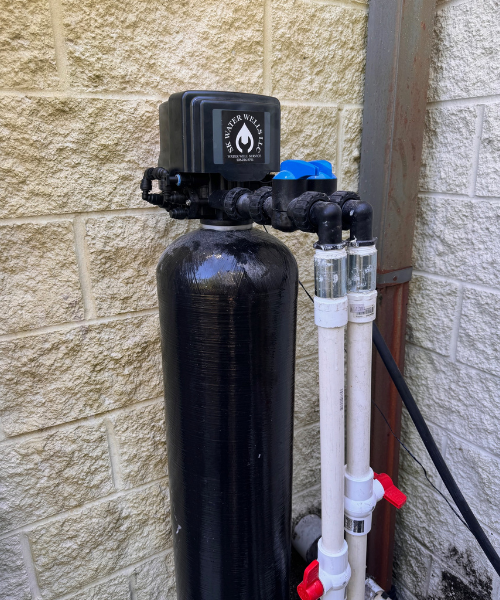 A black water heater next to a brick wall